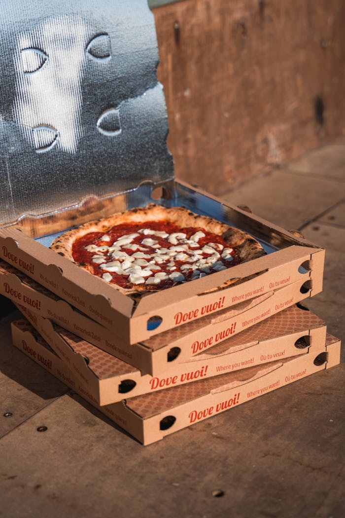 Delicious pizza in an open box atop stacked boxes, perfect for food delivery.